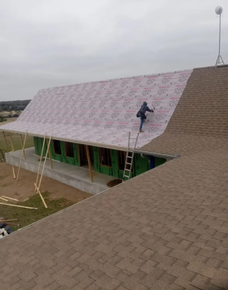 Worker preparing underlayment for a metal roof installation in Olney